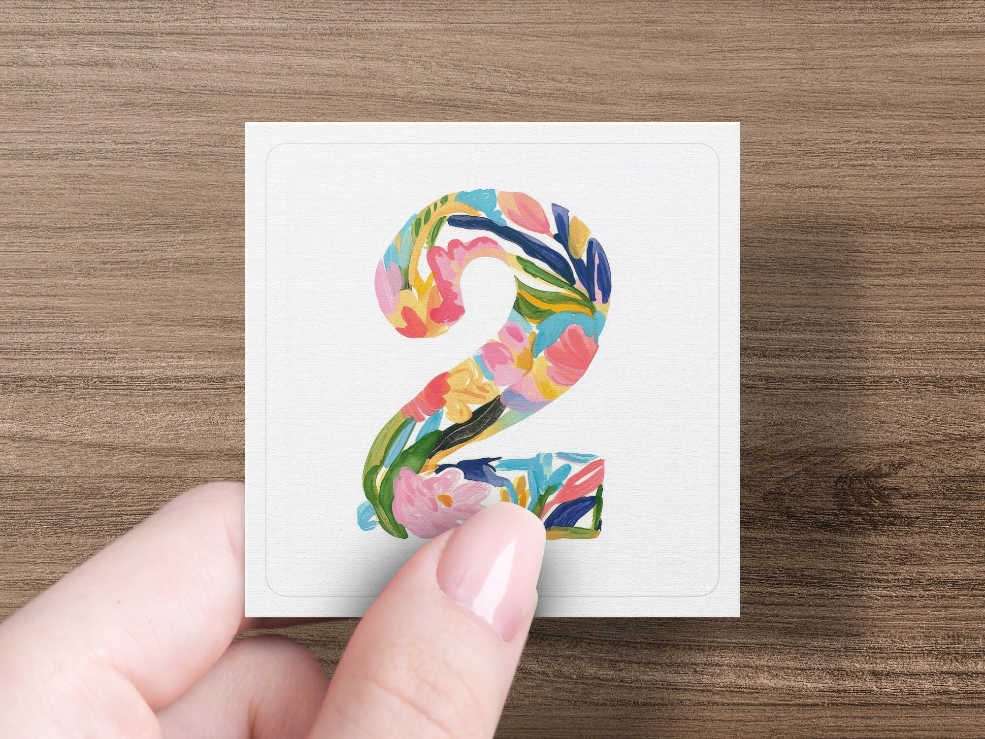 Number 2 in colorful floral watercolor painting held by a hand.