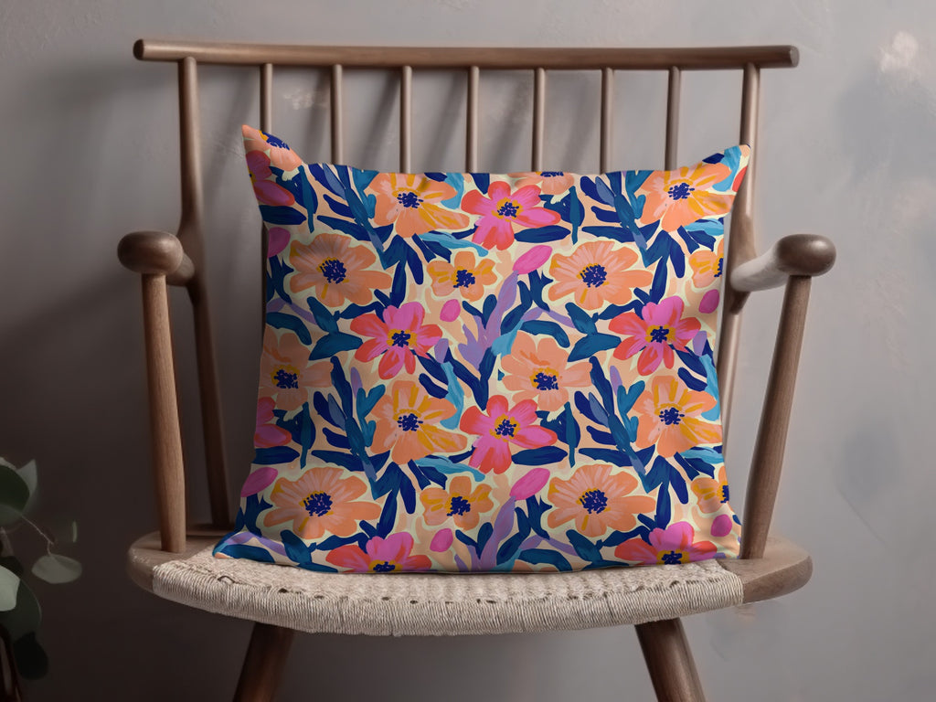 Floral pattern throw pillow with pink, orange, and blue flowers on a cream background.