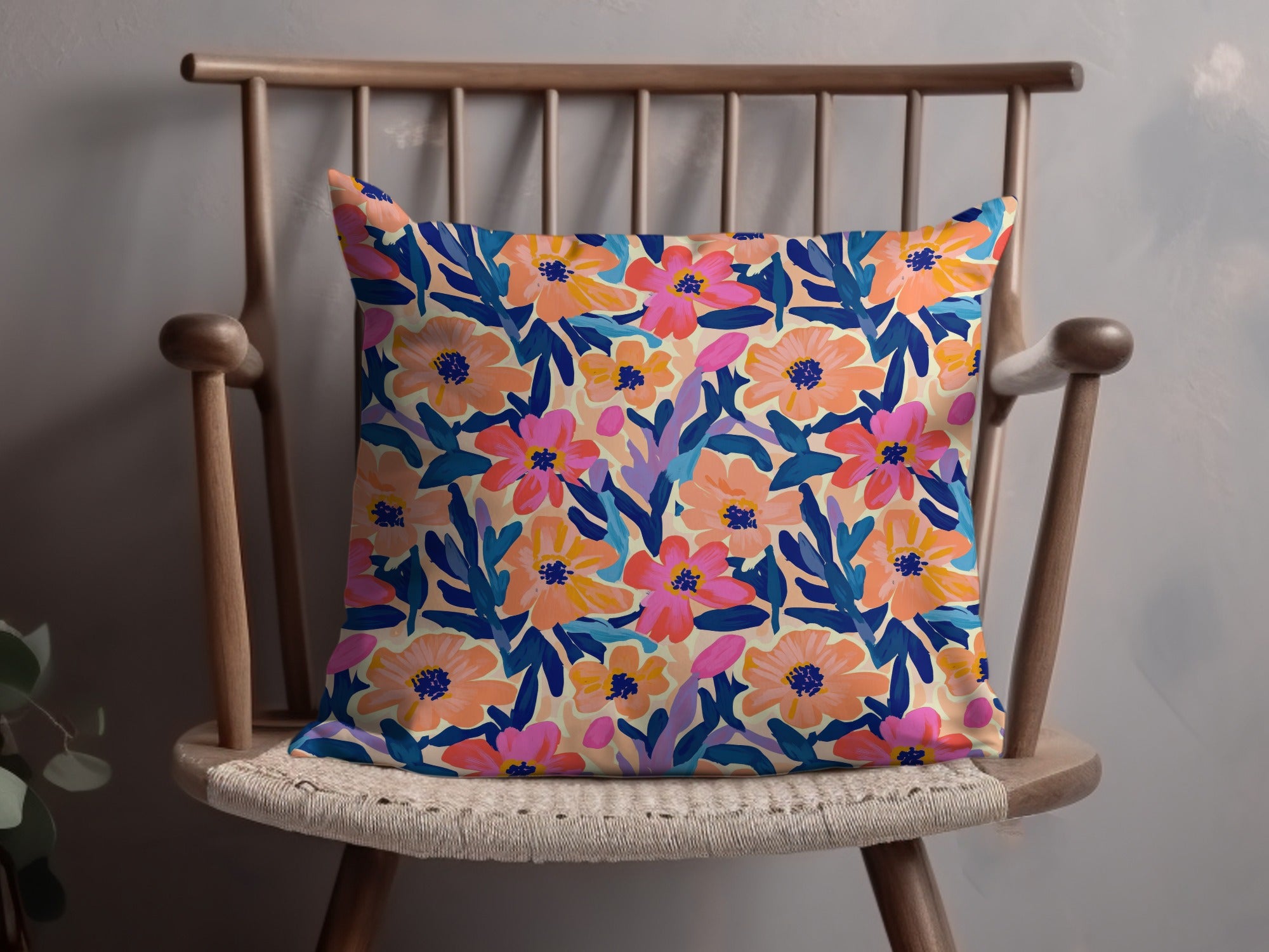 Floral pattern throw pillow with pink, orange, and blue flowers on a cream background.