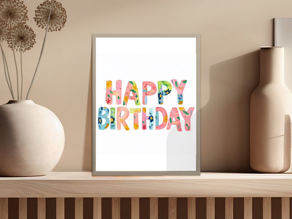 Colorful "Happy Birthday" text on framed art against a neutral background.