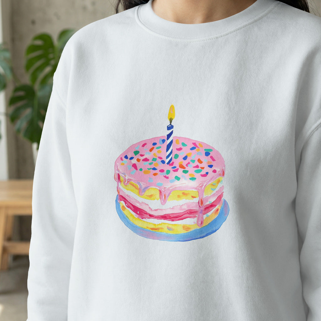 Watercolor birthday cake with pink frosting and a lit candle.