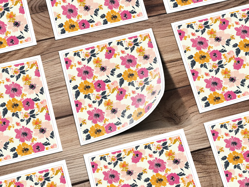 Scattered floral patterned cards with pink, orange, and yellow flowers on wood.
