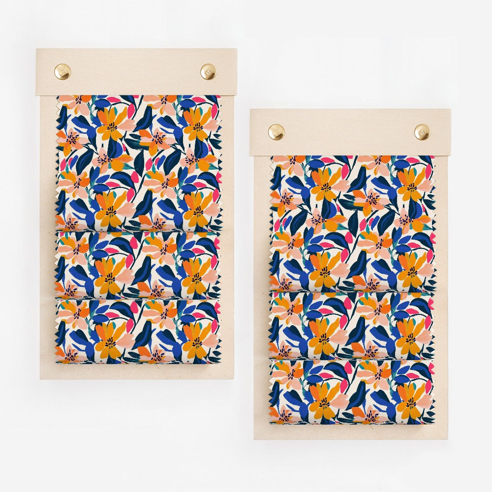 Two swatches of fabric with a colorful floral pattern on wooden clips.