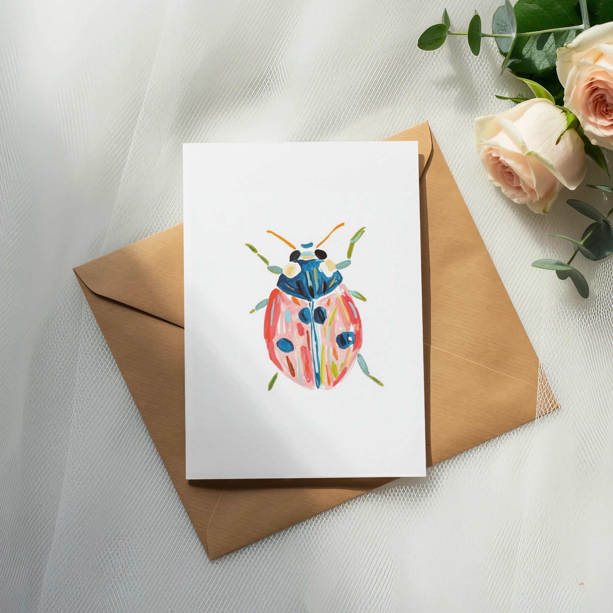Hand-painted ladybug illustration on a card with a kraft envelope and roses.