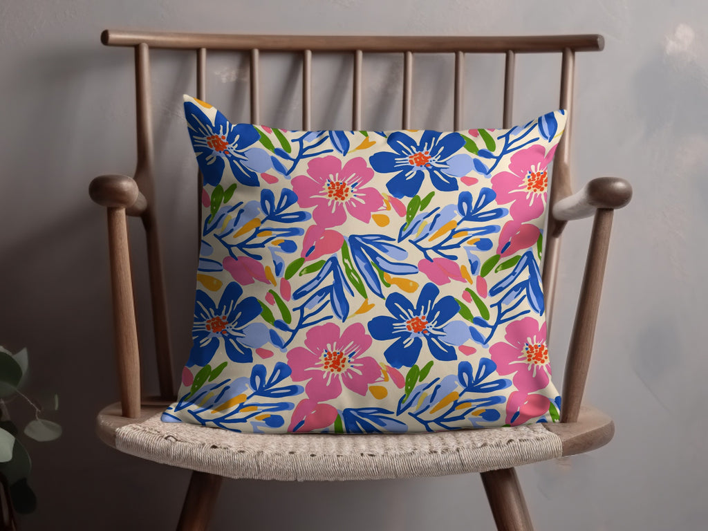 Floral patterned throw pillow with pink and blue flowers on a wooden chair.
