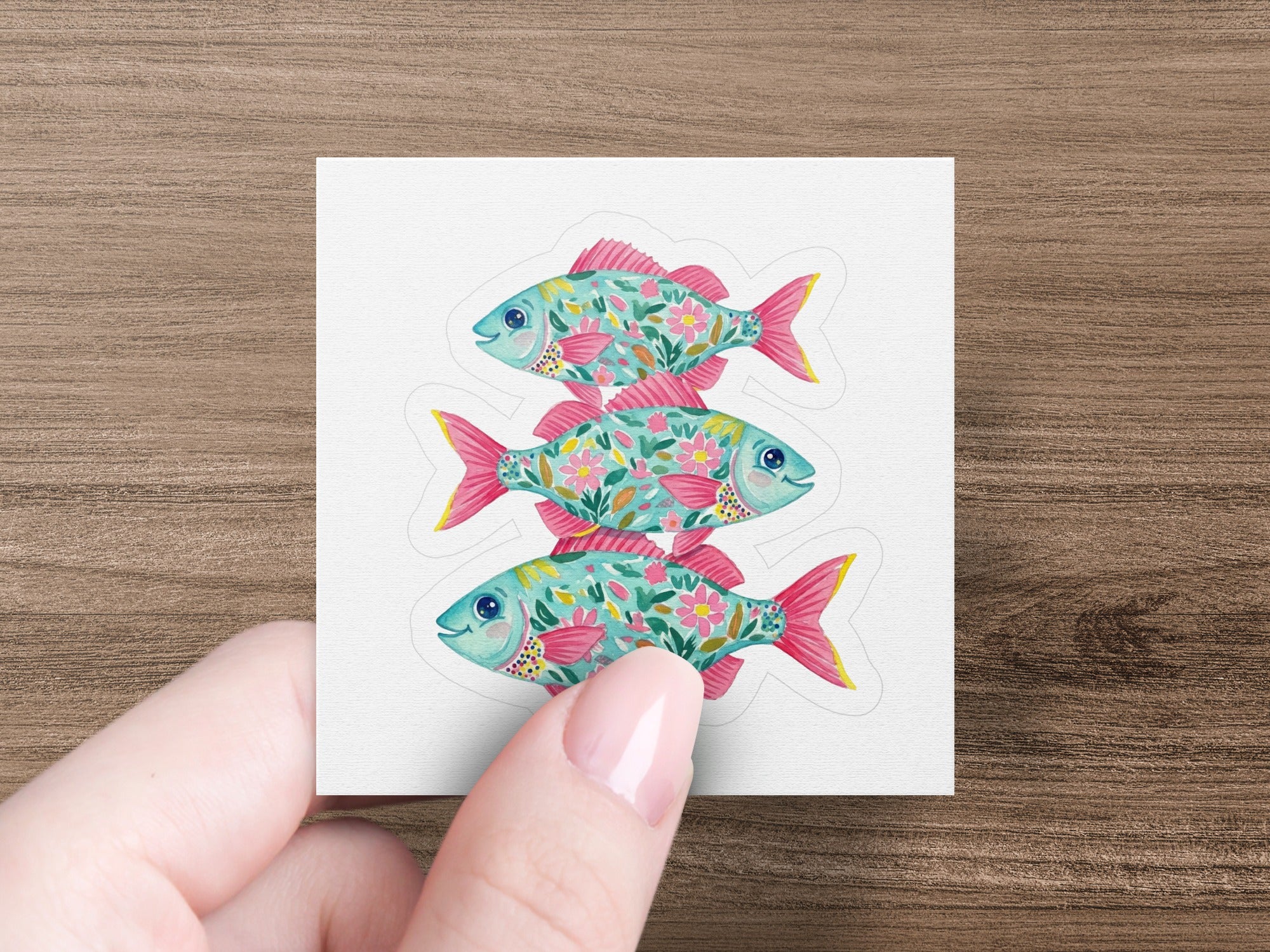 Three stylized teal and pink fish stacked vertically with floral patterns.