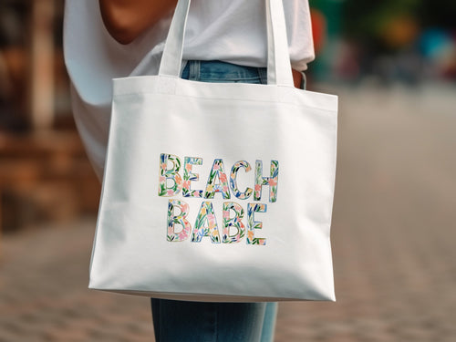 White tote bag with "BEACH BABE" text in floral pattern.