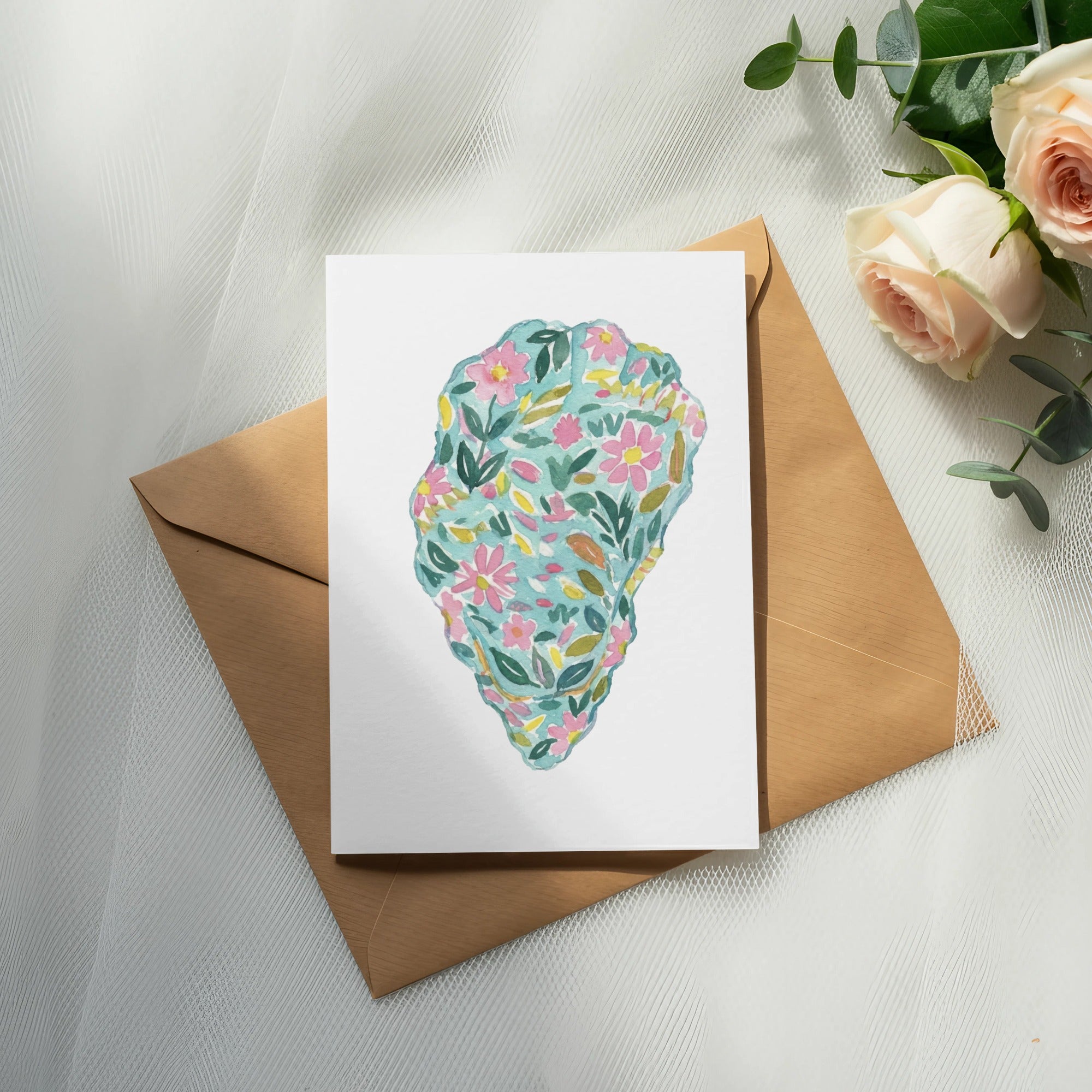 Watercolor floral illustration on a card placed on a brown envelope.
