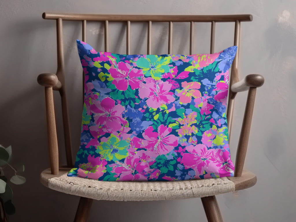 Throw pillow with a vibrant pink and blue floral hibiscus pattern on dark blue.