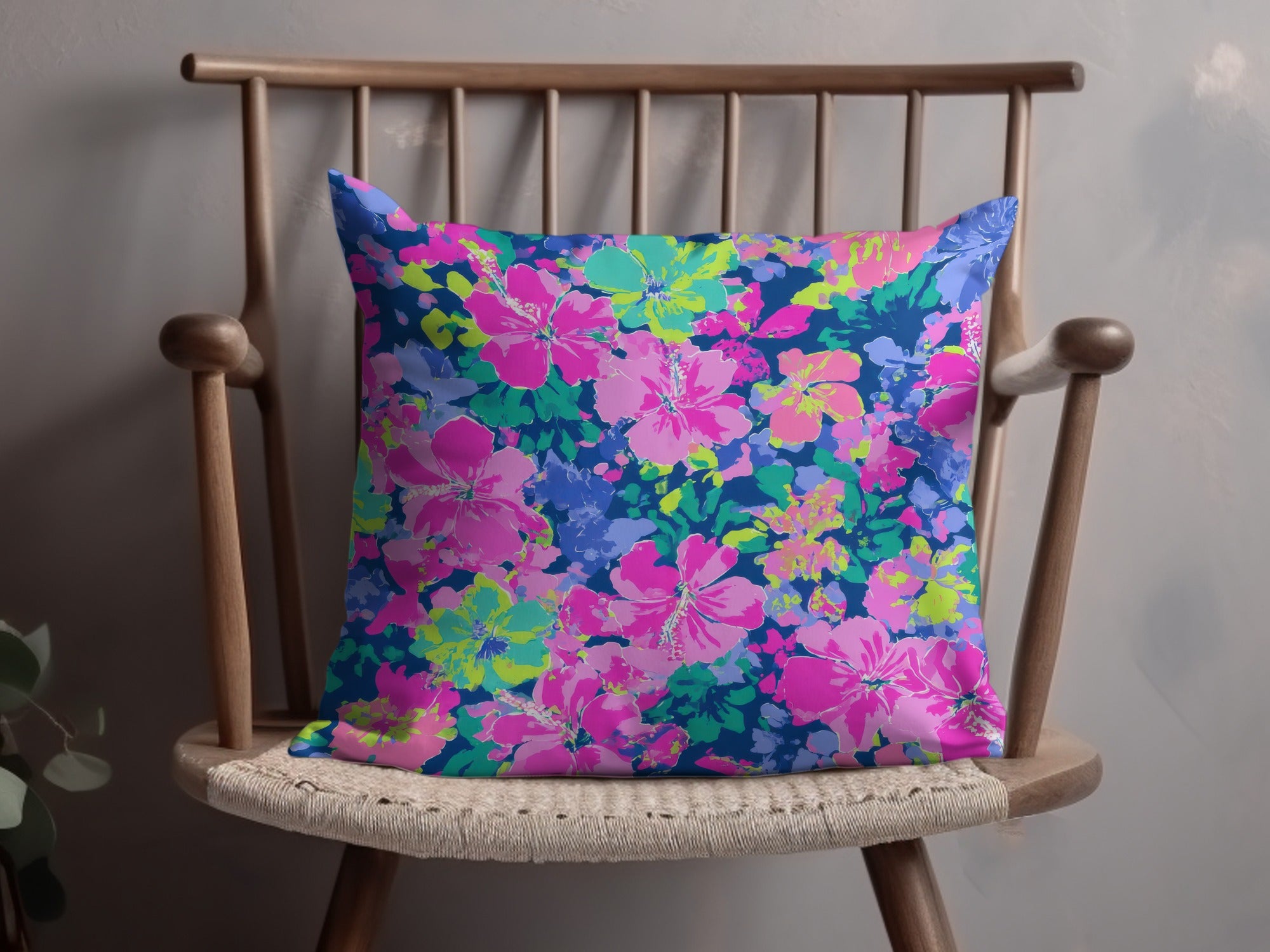 Throw pillow with a vibrant pink and blue floral hibiscus pattern on dark blue.