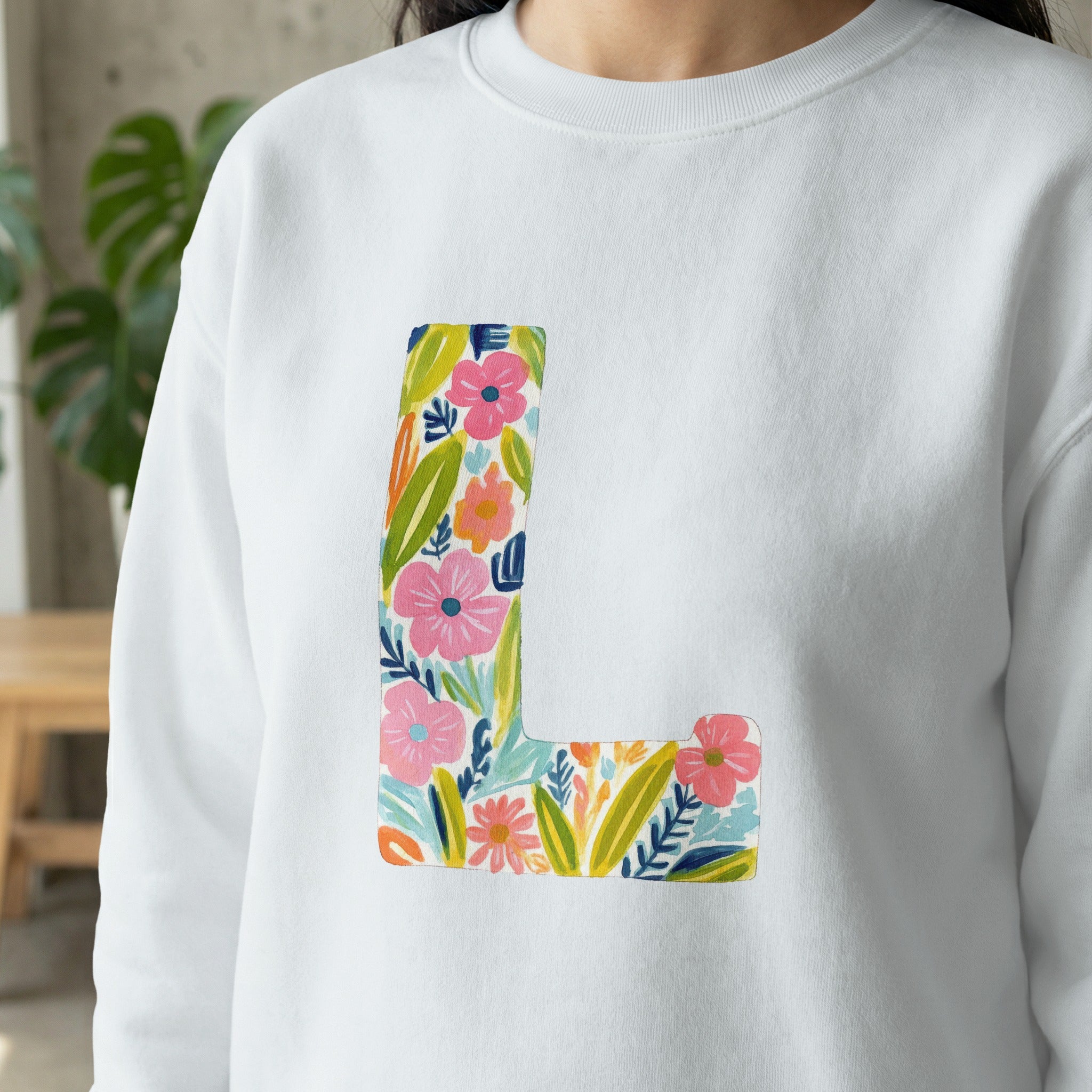 White sweatshirt with a large floral letter "L" design.