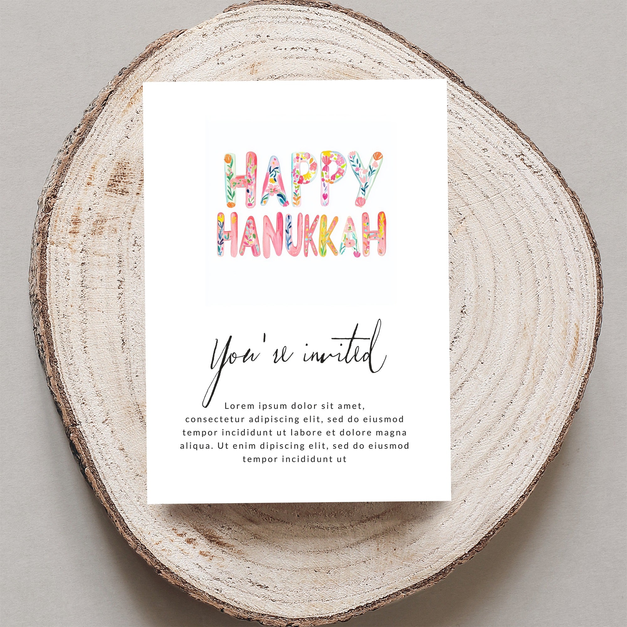Happy Hanukkah invitation with floral lettering, reads "You're invited"