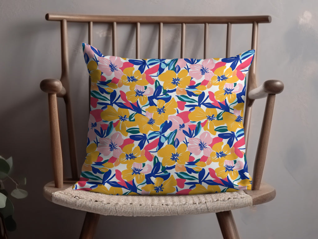 Floral pillow with pink, yellow, and blue flowers on a wooden chair.
