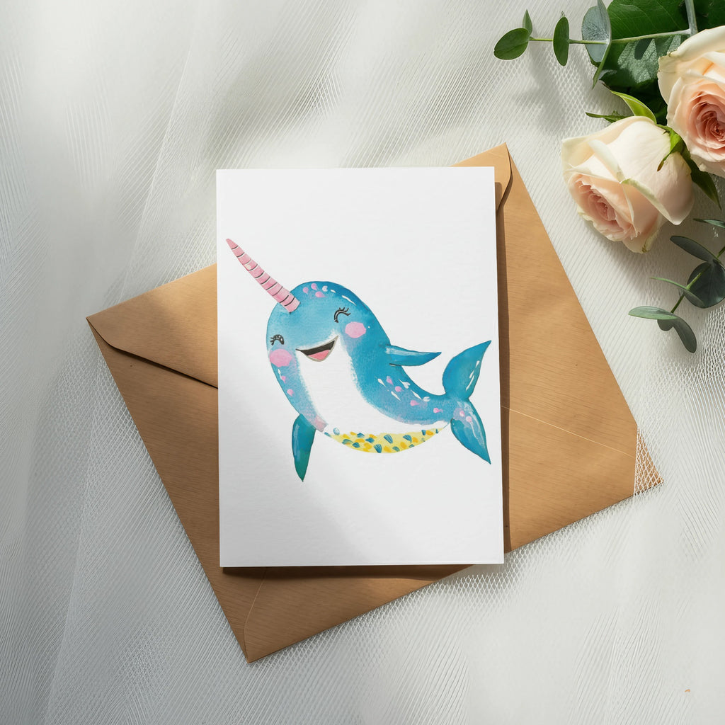 Cartoon narwhal with pink horn and blue spotted body on a card.