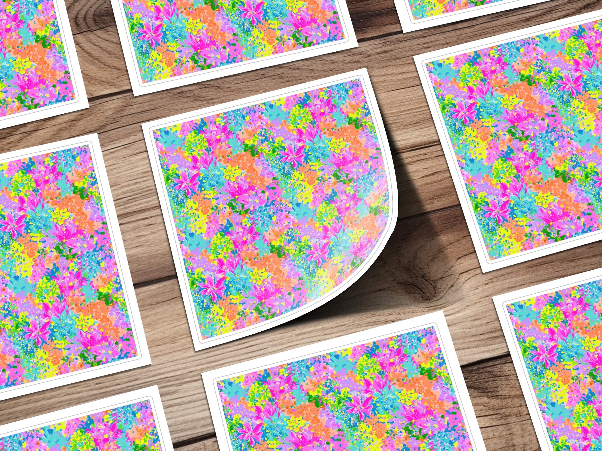 Colorful floral pattern on multiple square cards, some overlapping, on a wooden surface.