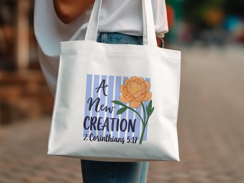 White tote bag with orange flower and "A New CREATION" text.