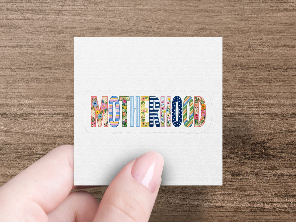 "Motherhood" text in colorful, patterned lettering on a white background.