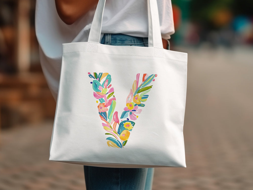 White tote bag with colorful floral letter "V" design.