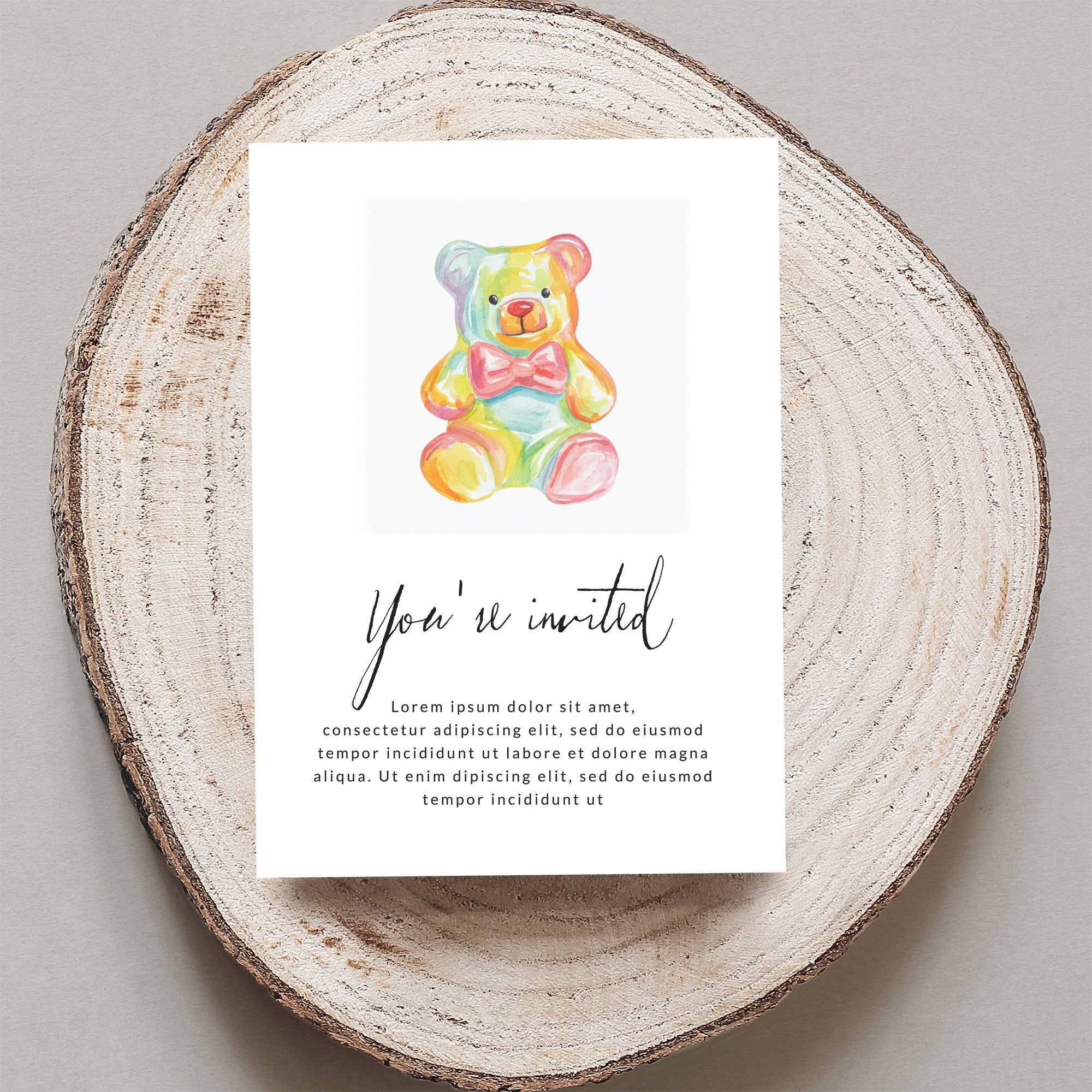 Invitation with a rainbow teddy bear and "You're invited" text.