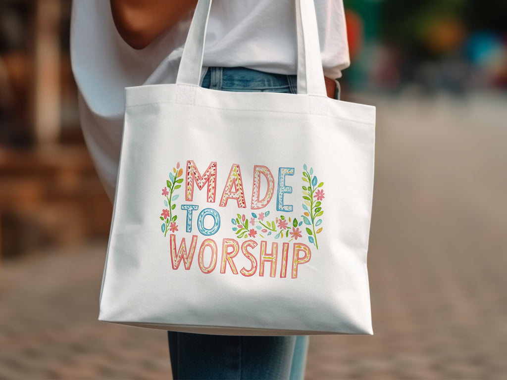 White tote bag with "Made to Worship" text and floral accents.