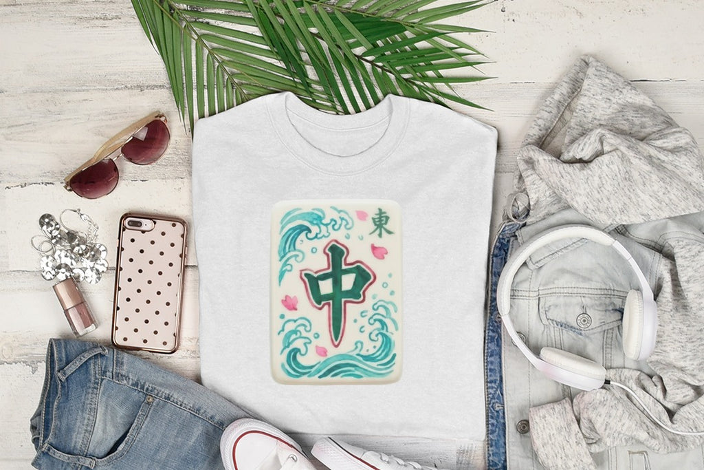 White t-shirt with green mahjong tile on wavy blue background, styled with jeans and headphones.