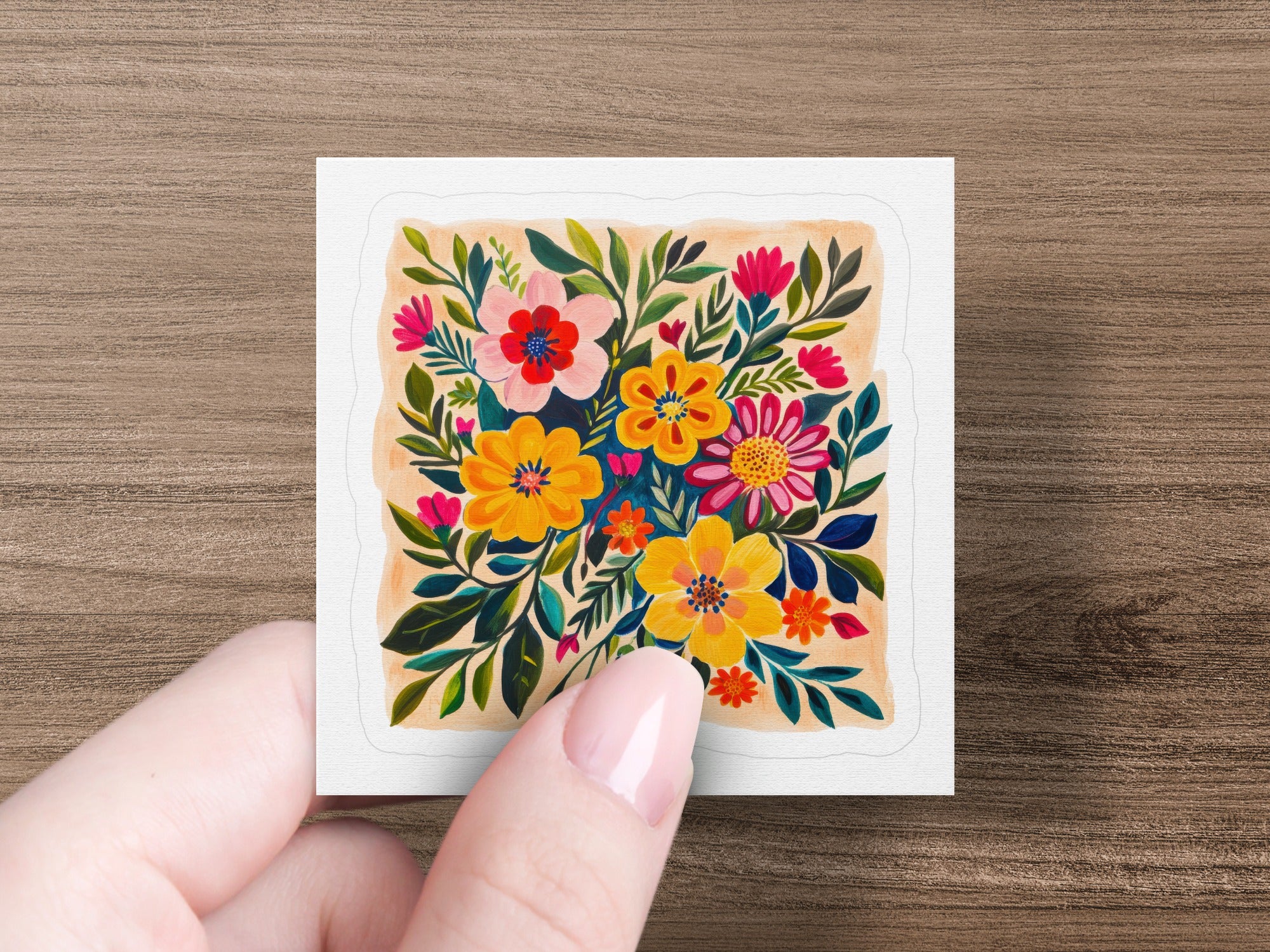 Hand holding square print of colorful folk art floral arrangement.