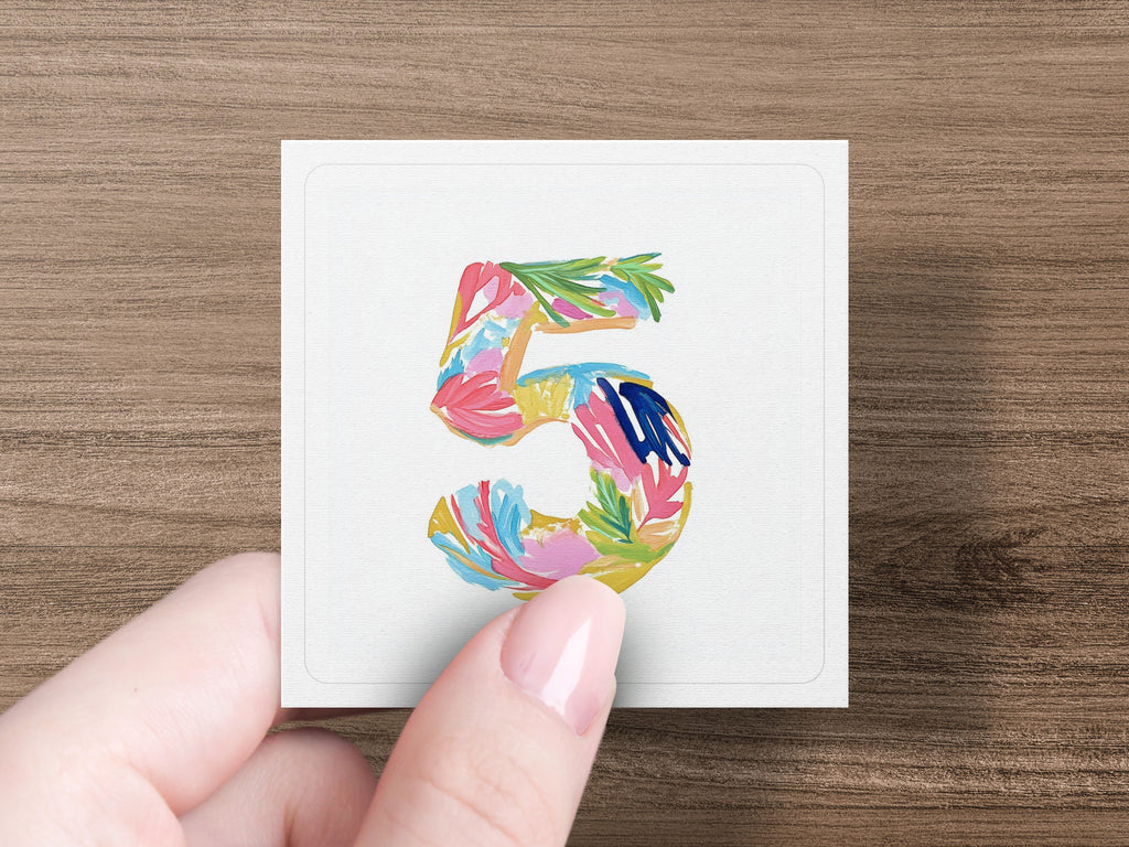 Hand holds card with colorful painted number five.