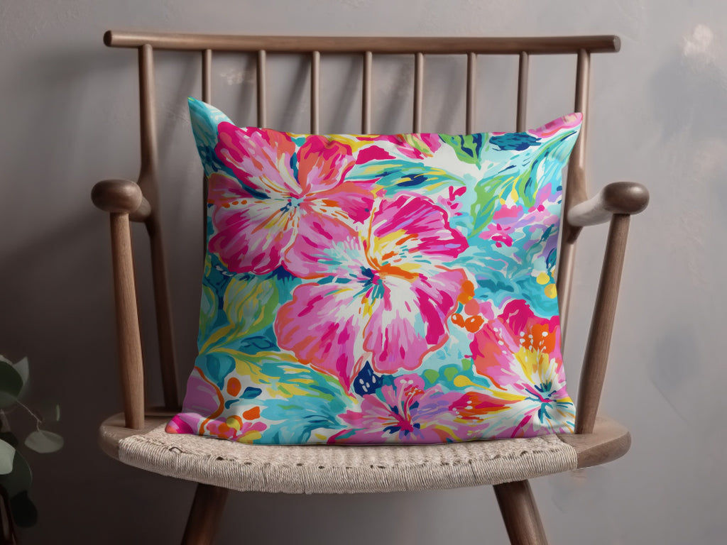 Bright floral throw pillow with pink, blue, and yellow hibiscus flowers.