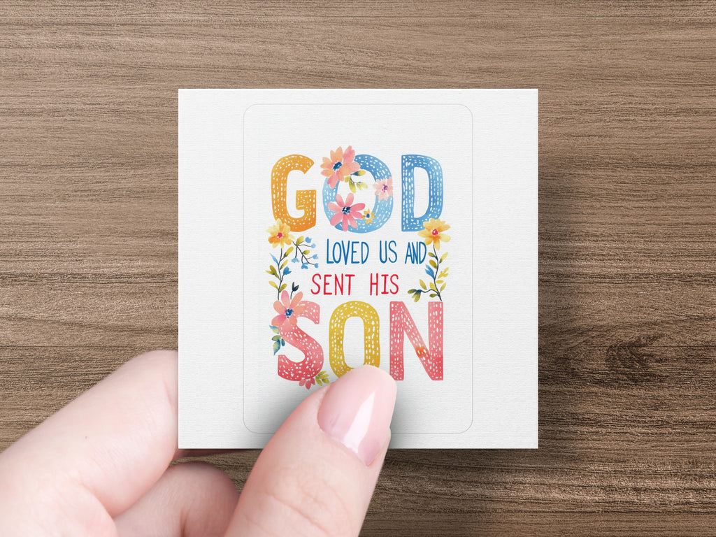 Square sticker with "God loved us and sent his son" in colorful floral lettering.
