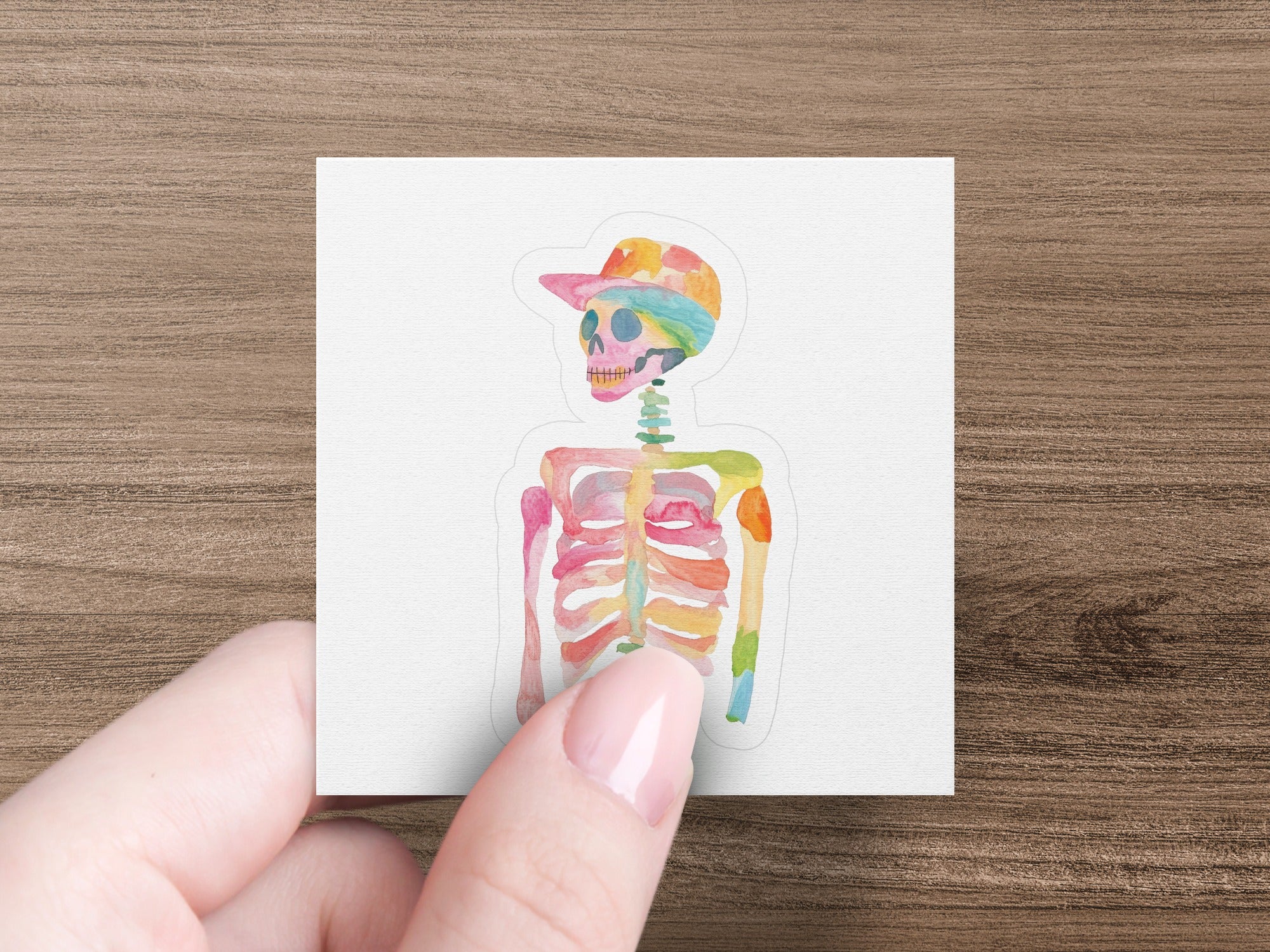 Watercolor skeleton wearing a colorful baseball cap.