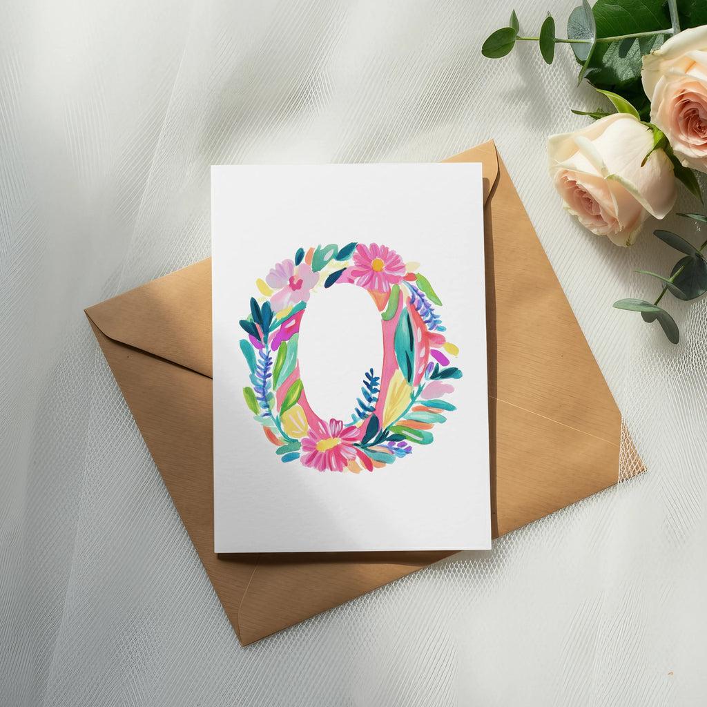 Watercolor letter O surrounded by flowers on a card, with an envelope and roses.
