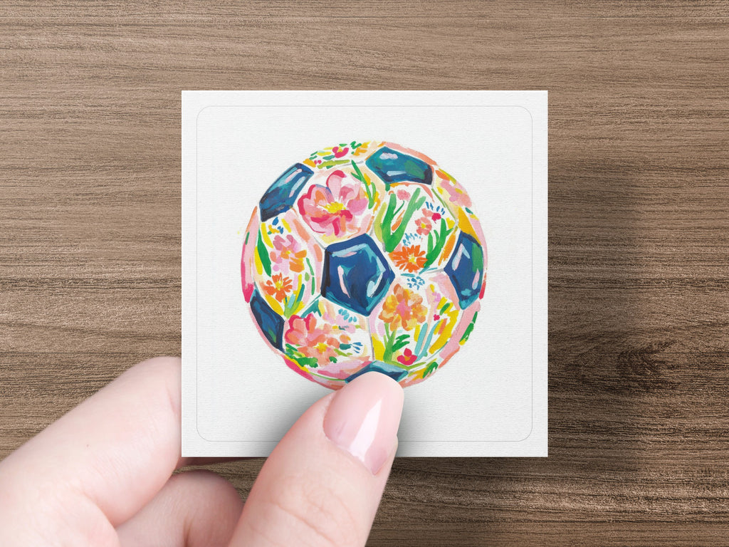 Watercolor soccer ball with floral pattern held by a hand.