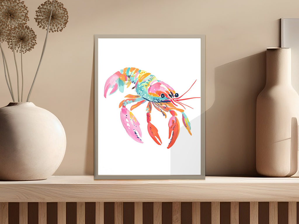 Colorful watercolor lobster art in a light frame on a shelf.