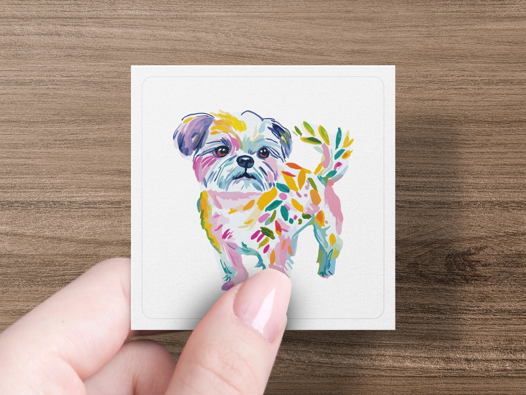 Hand holding square card featuring colorful painted dog with leaf-like accents.