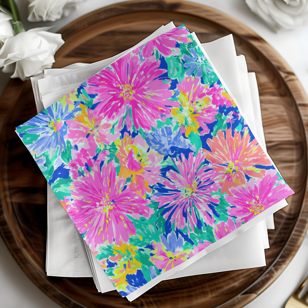 Colorful floral print napkins stacked on a wooden tray with white napkins.