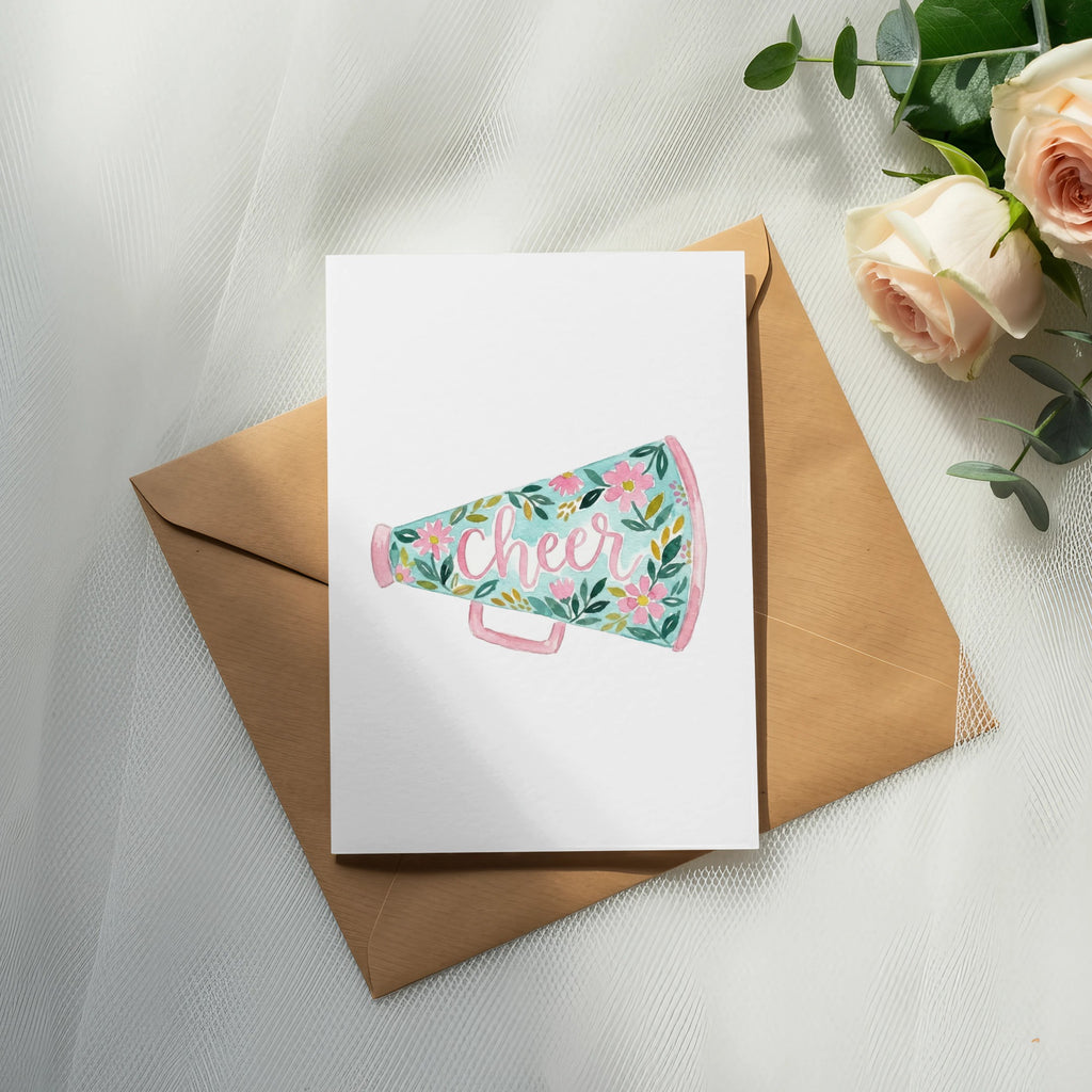Cheer megaphone with floral design on card atop envelope, with roses.