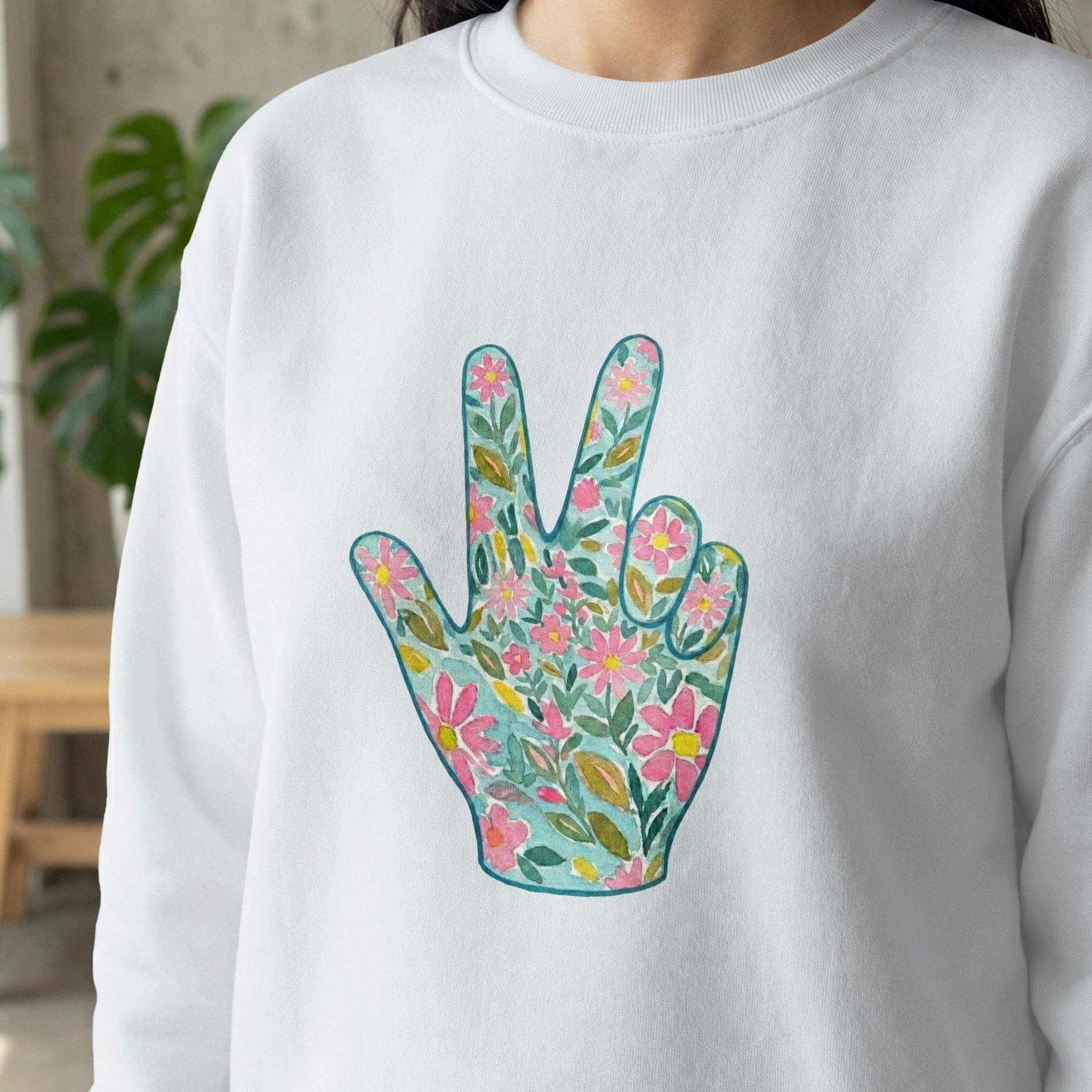 White sweatshirt with floral peace sign hand graphic.