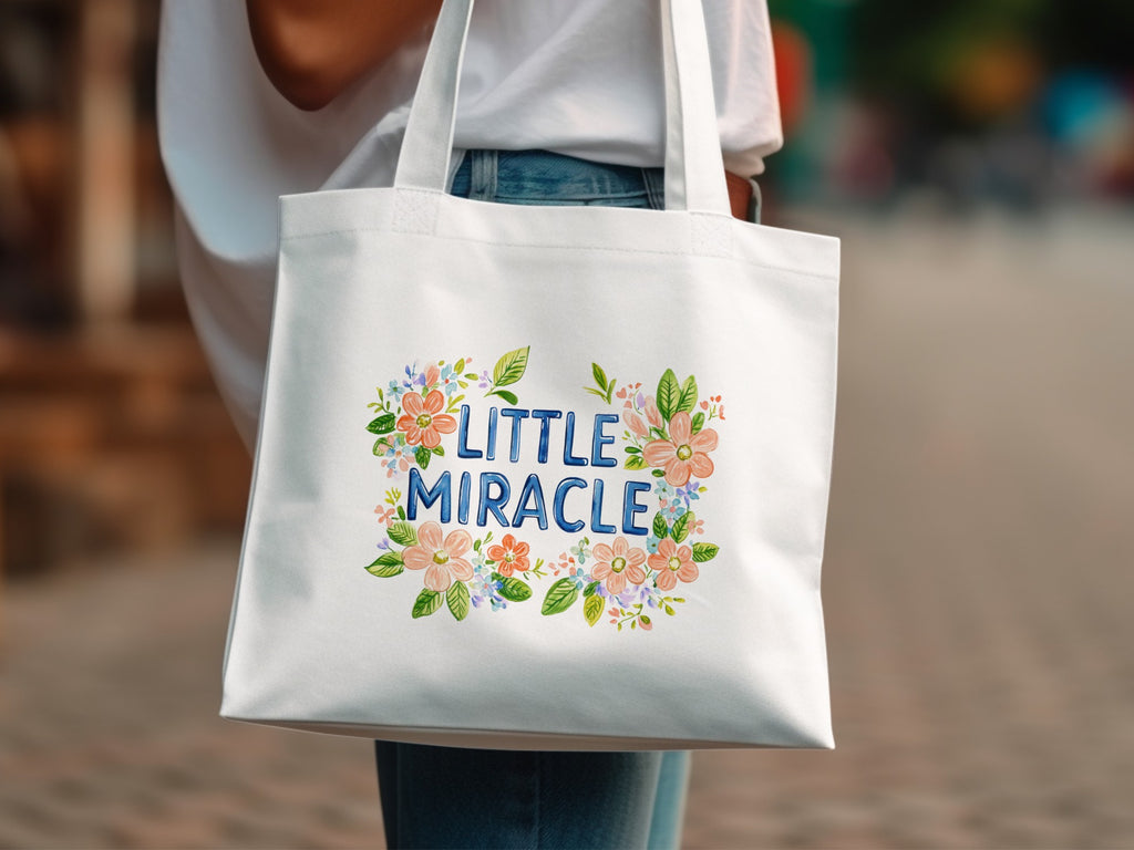 White canvas tote bag with "LITTLE MIRACLE" text and floral design.