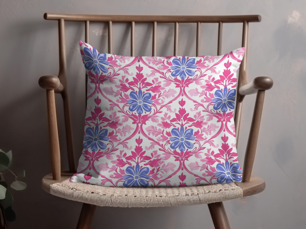 Decorative throw pillow with pink and blue floral damask pattern on a wooden chair.