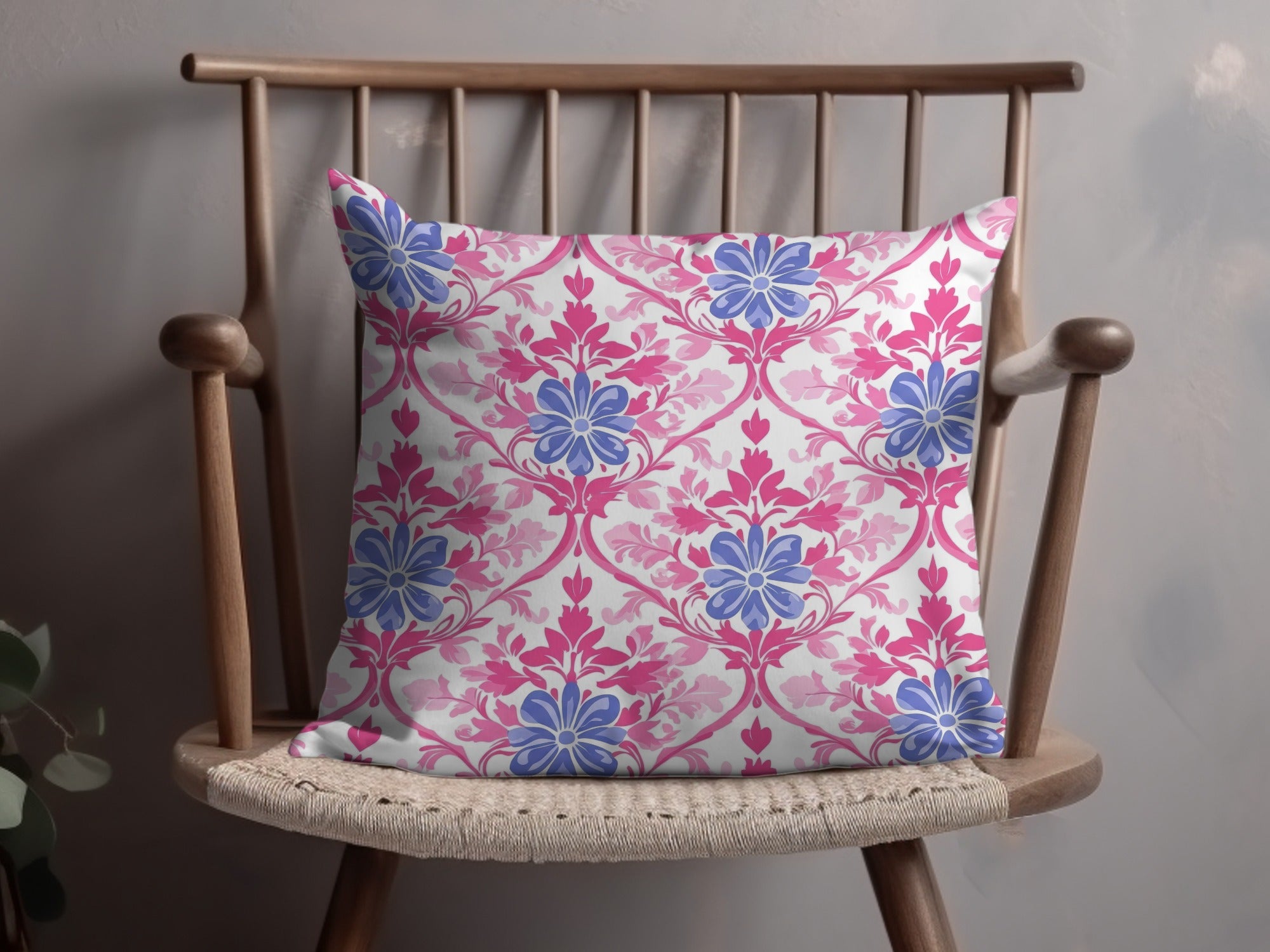 Decorative throw pillow with pink and blue floral damask pattern on a wooden chair.