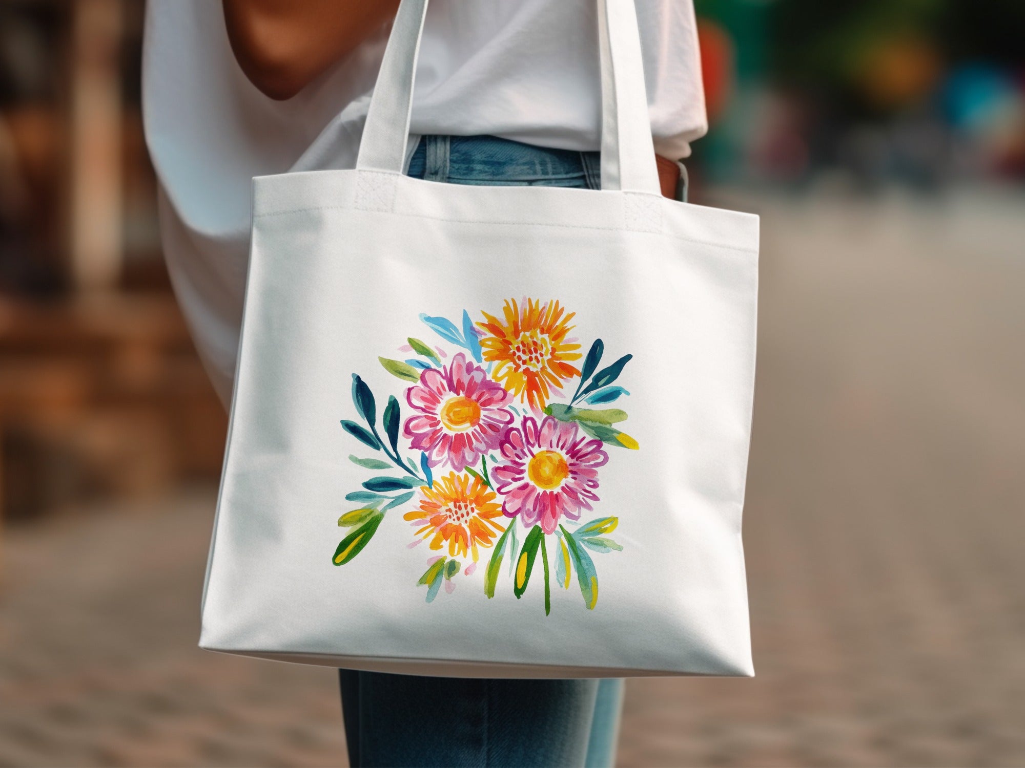White tote bag with a vibrant watercolor floral bouquet in pink, orange, and yellow.