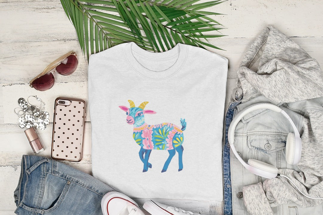 White t-shirt with a colorful patterned goat graphic, laid flat with accessories.