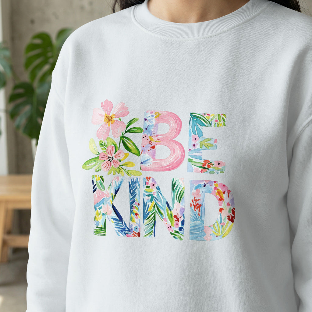 White sweatshirt with "BE KIND" in floral watercolor lettering.