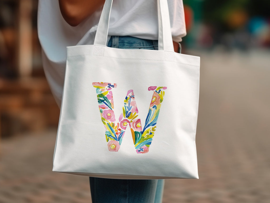 White tote bag with a large colorful floral letter "W" design.