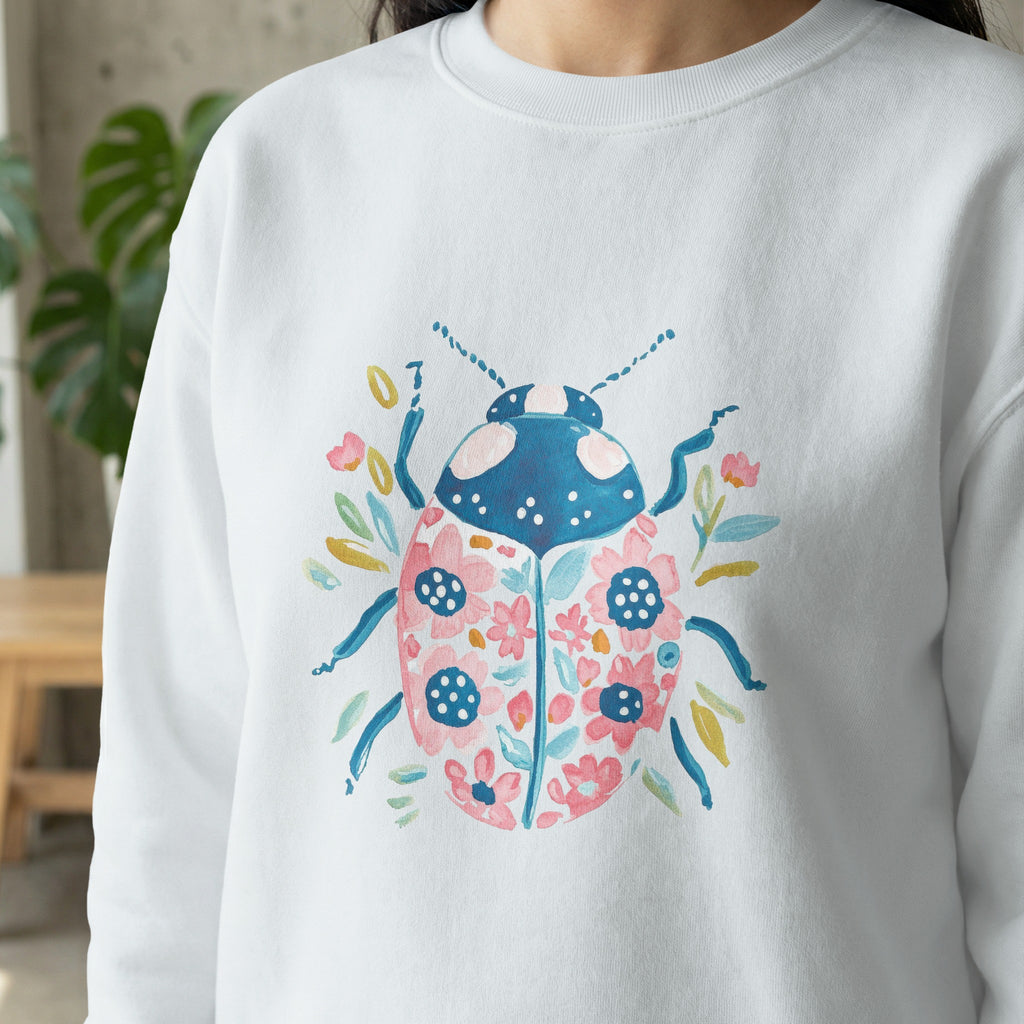 White sweatshirt with a watercolor ladybug and floral design.