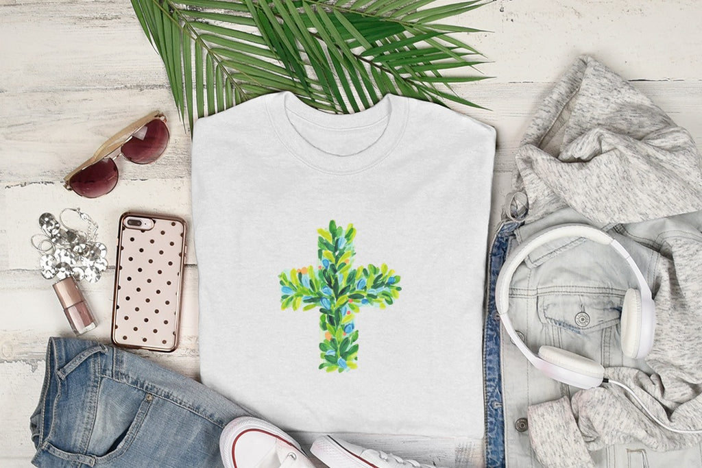 White t-shirt with a green and blue leaf cross design.
