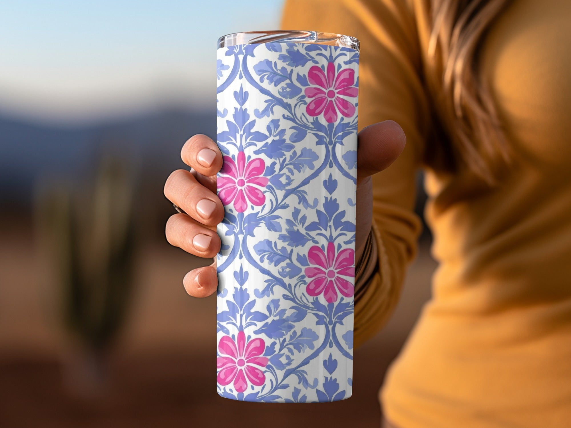 Person holding a blue and white floral patterned tumbler with pink flowers.