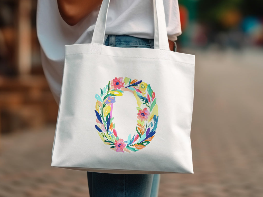 White tote bag with a colorful floral letter O design.