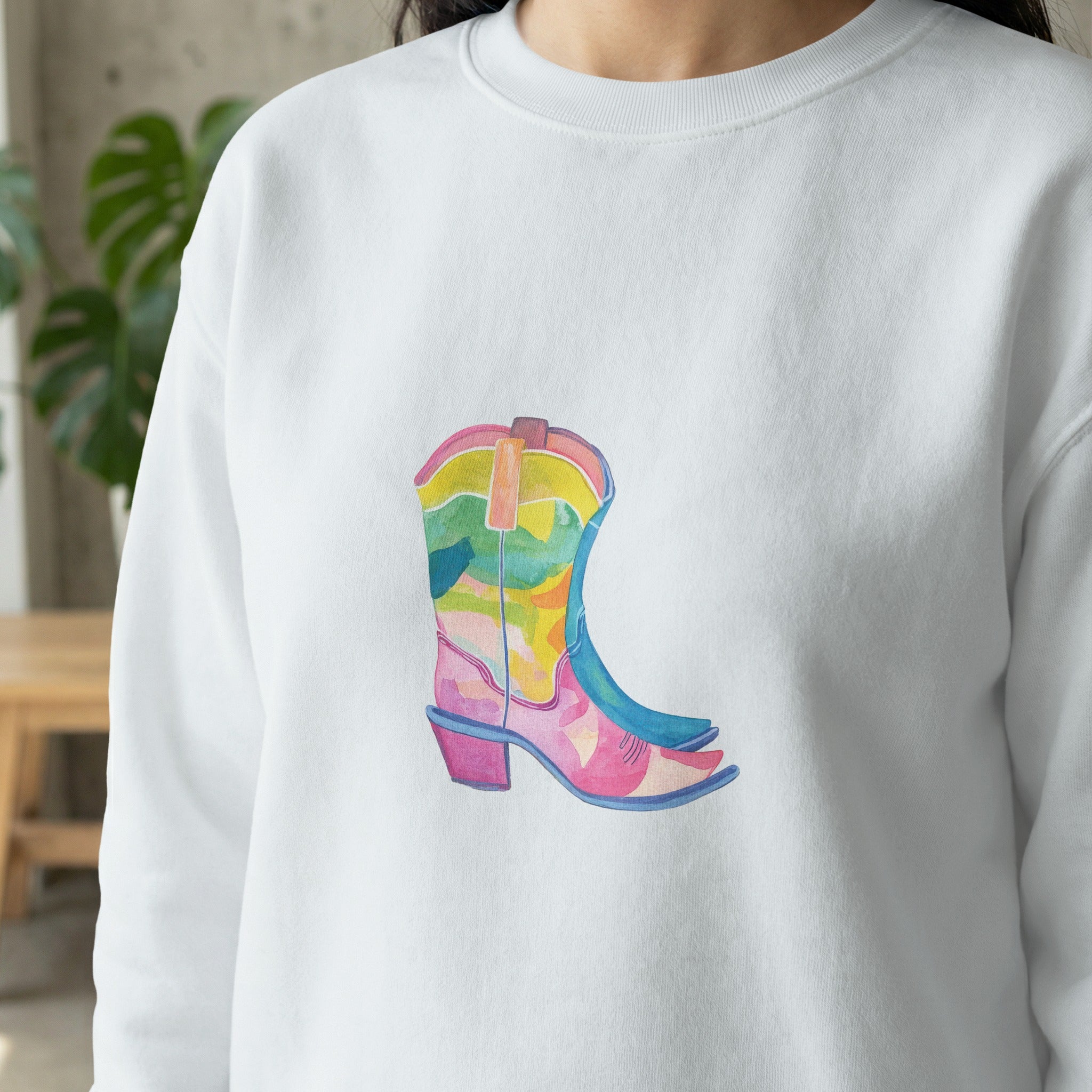 White sweatshirt with a colorful watercolor cowboy boot graphic.