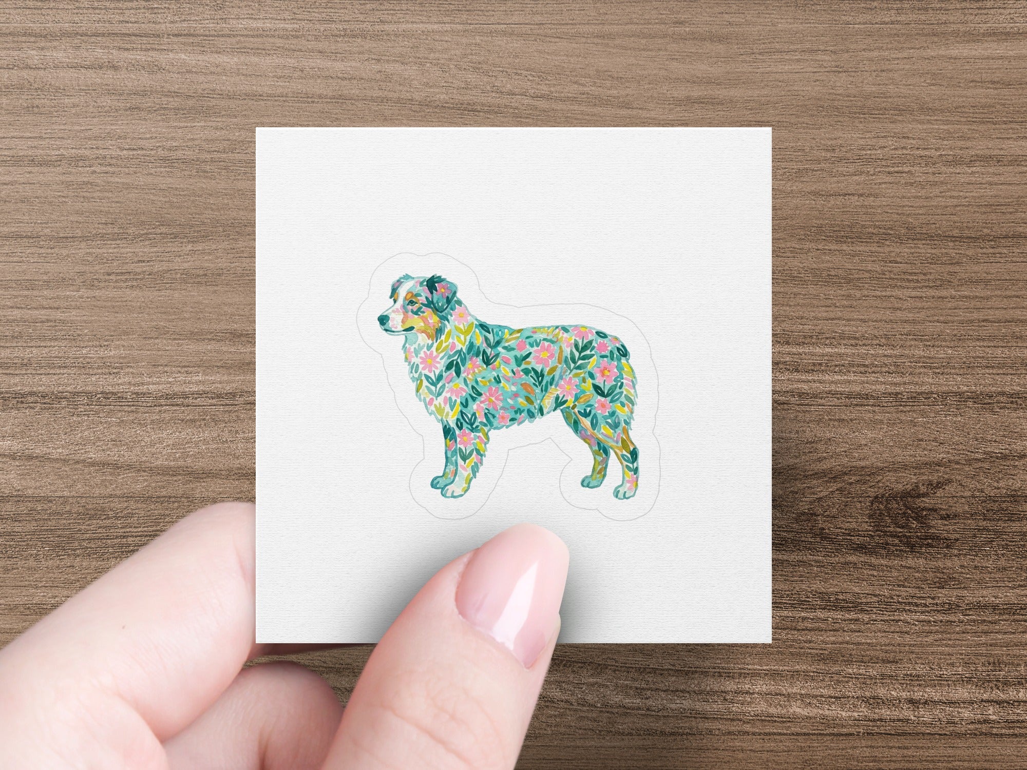 Dog silhouette filled with a floral pattern, held by a hand.